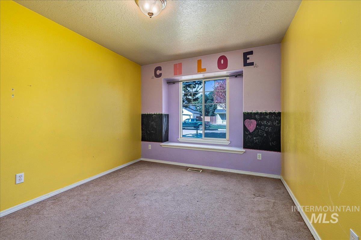 Empty room featuring a textured ceiling and carpet