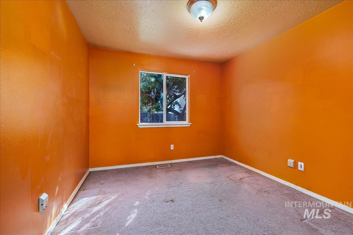 Carpeted empty room featuring a textured ceiling and baseboards