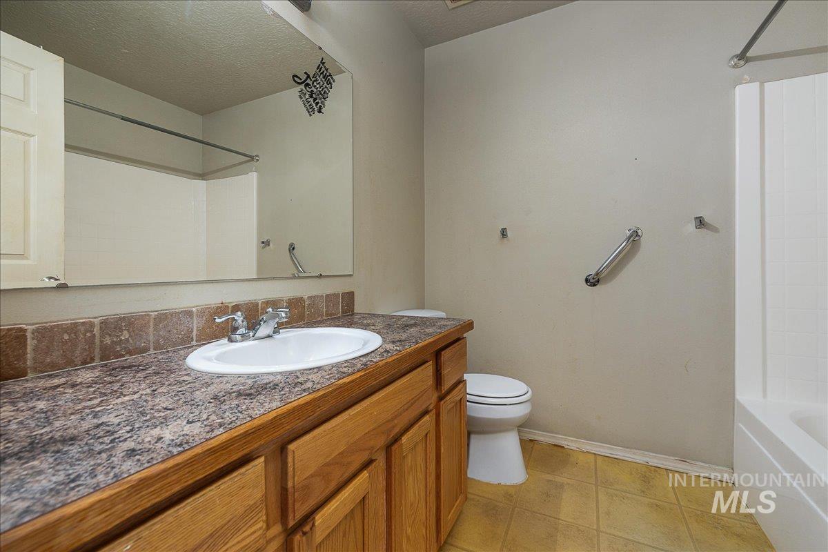 Bathroom with light tile patterned floors, vanity, a textured ceiling, and tub / shower combination