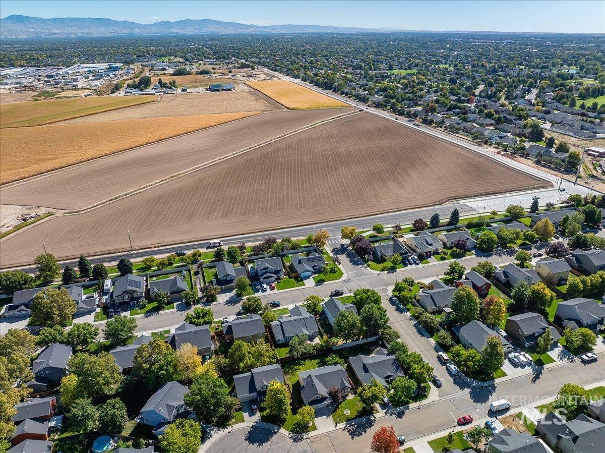 Aerial view of property's location featuring nearby suburban area, a mountain backdrop, and abundant farmland
