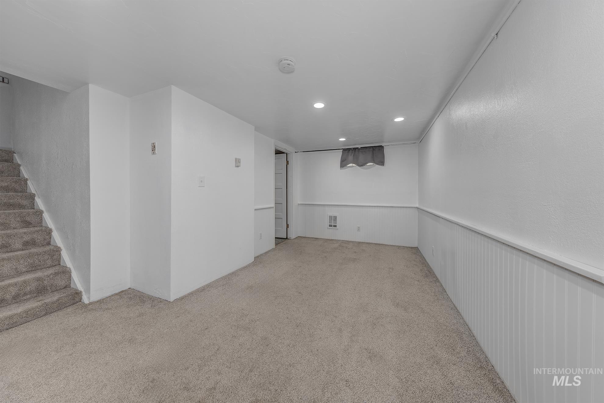 Carpeted empty room with recessed lighting and stairway
