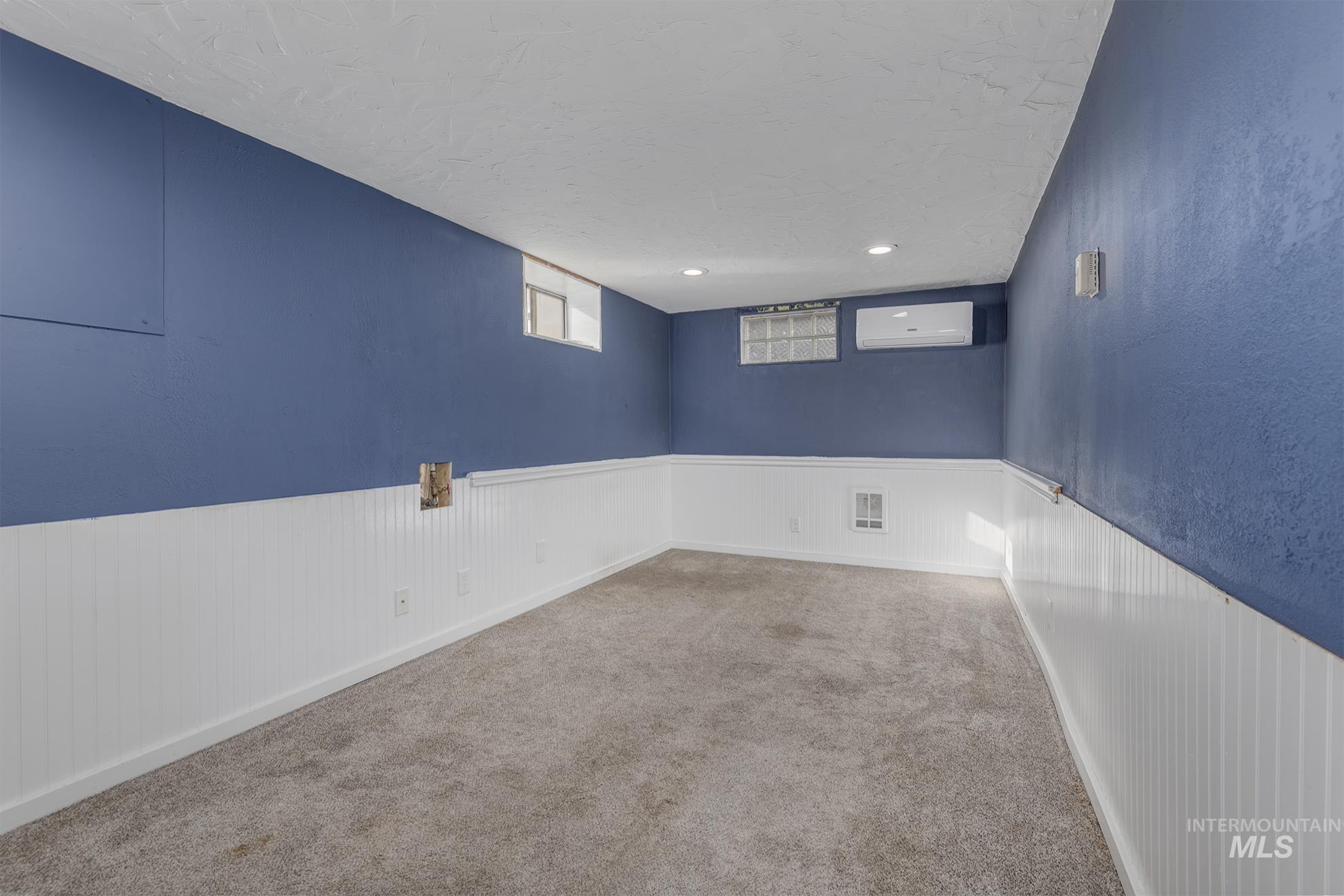 Spare room with carpet, a wainscoted wall, a textured ceiling, an AC wall unit, and recessed lighting