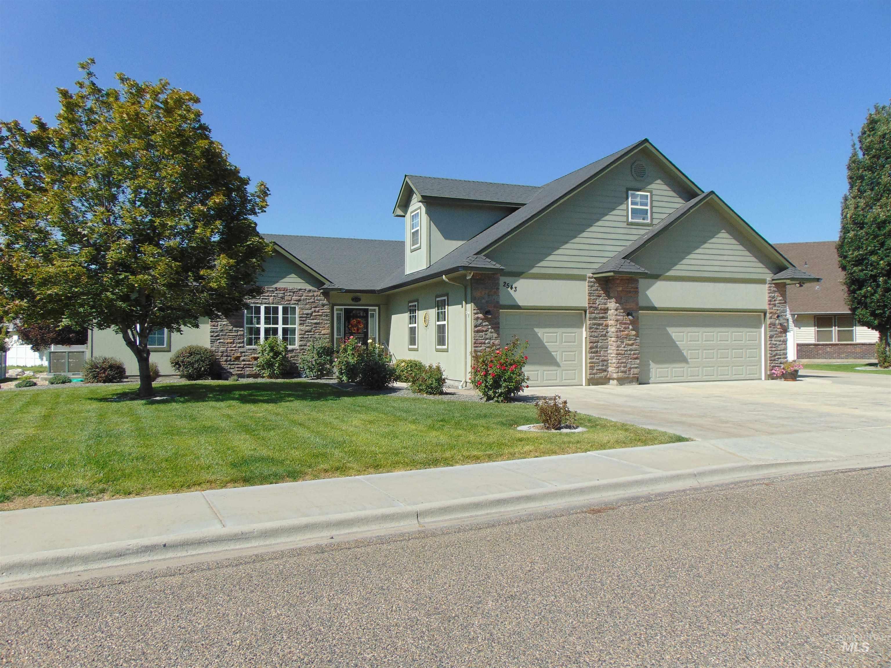 View of front of home with stone siding, driveway, a front lawn, and stucco siding