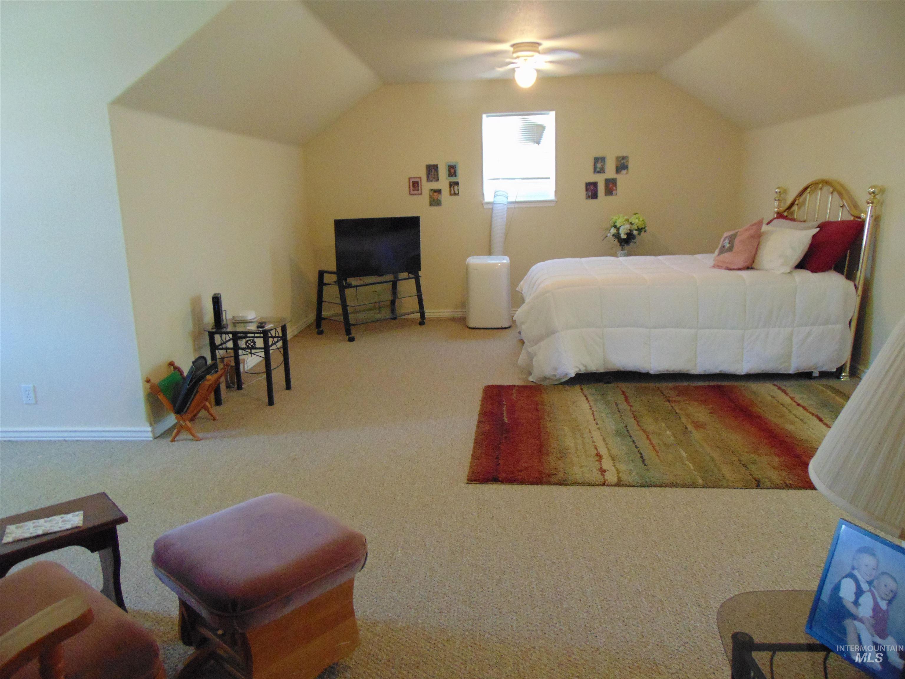 Carpeted bedroom with lofted ceiling and ceiling fan