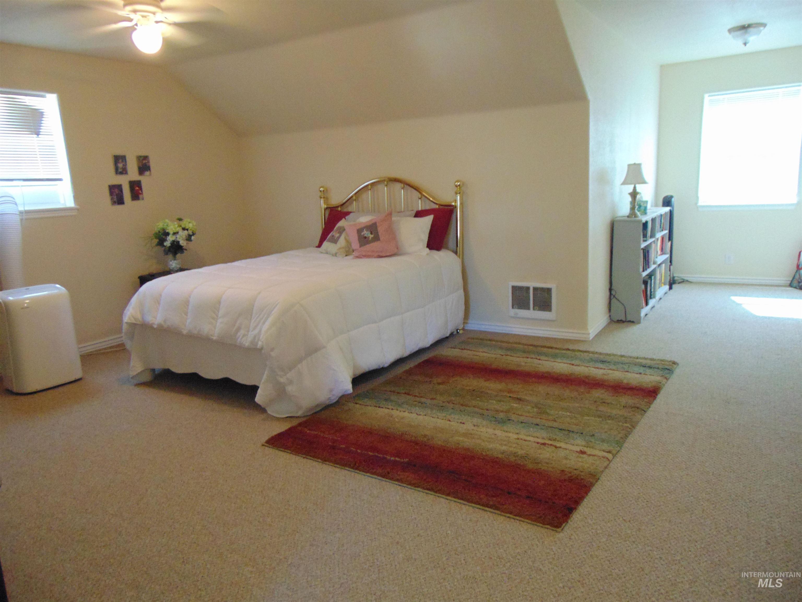 Carpeted bedroom with ceiling fan and vaulted ceiling