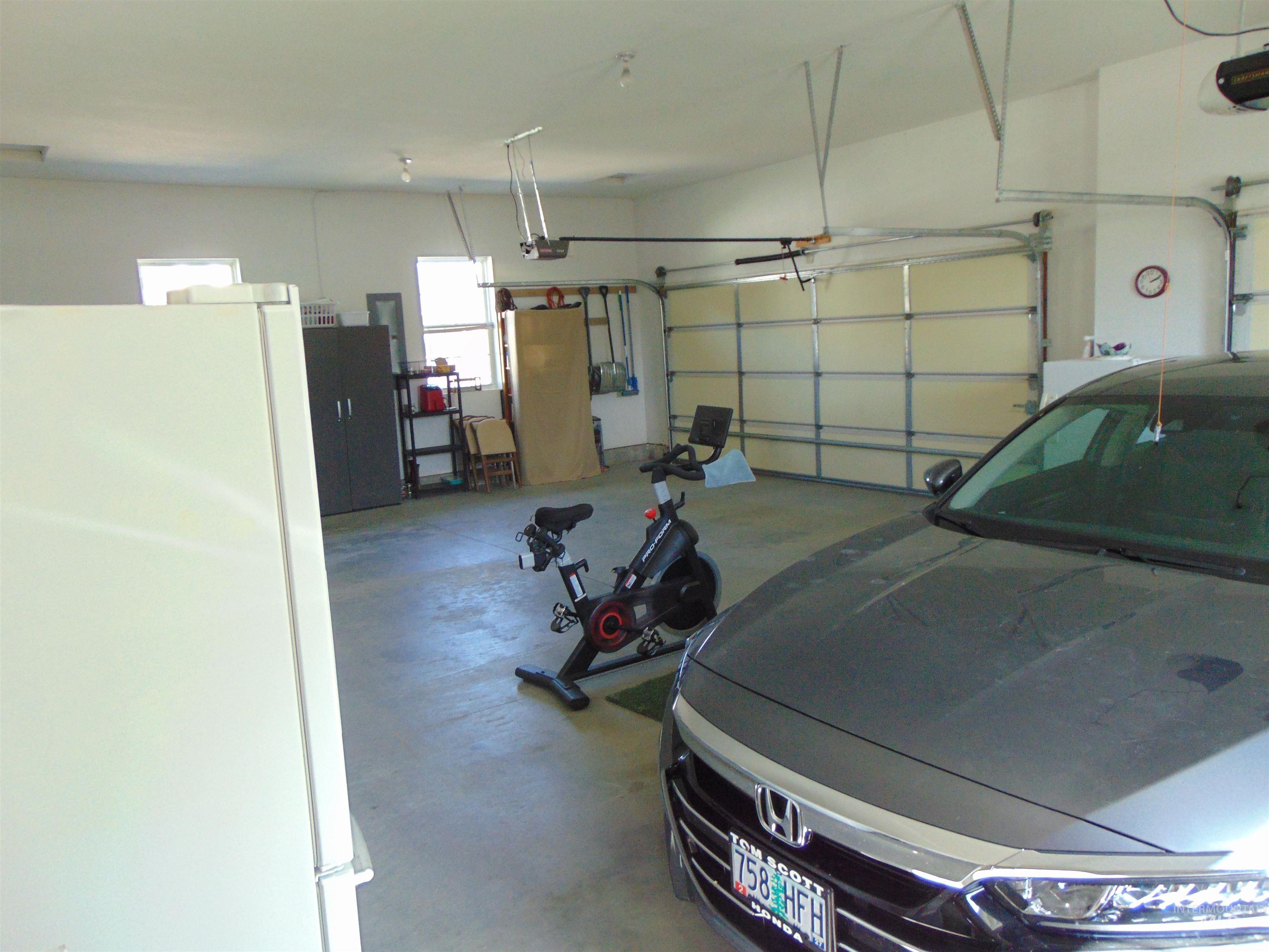 Garage featuring freestanding refrigerator, a garage door opener, and electric panel