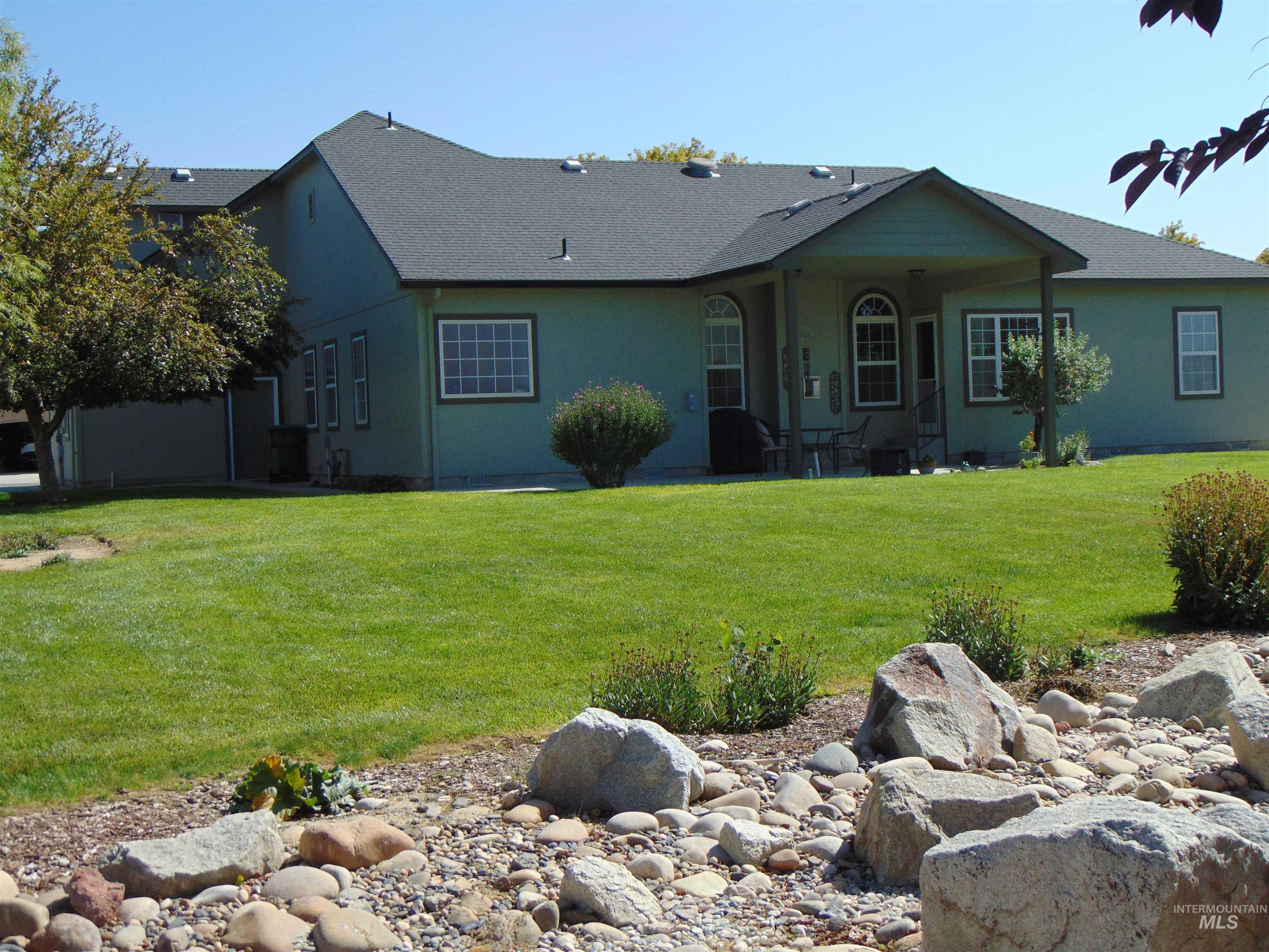 View of front of home featuring a front lawn, a patio, stucco siding, and a shingled roof