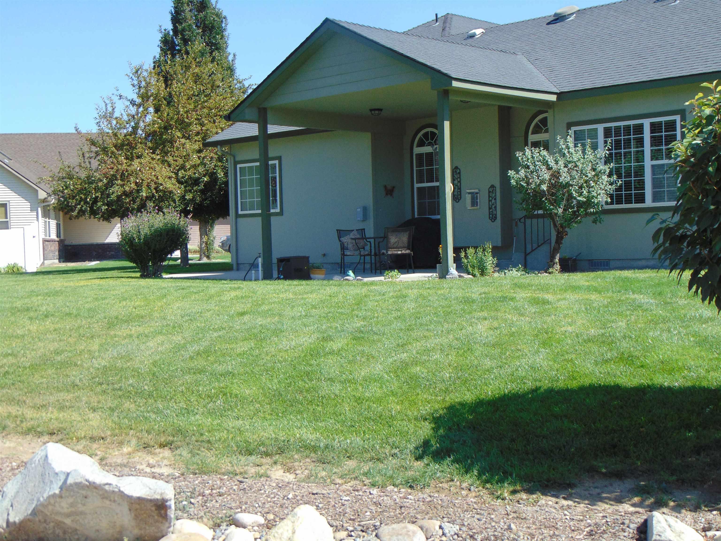 Rear view of house with a patio area, roof with shingles, a lawn, and stucco siding