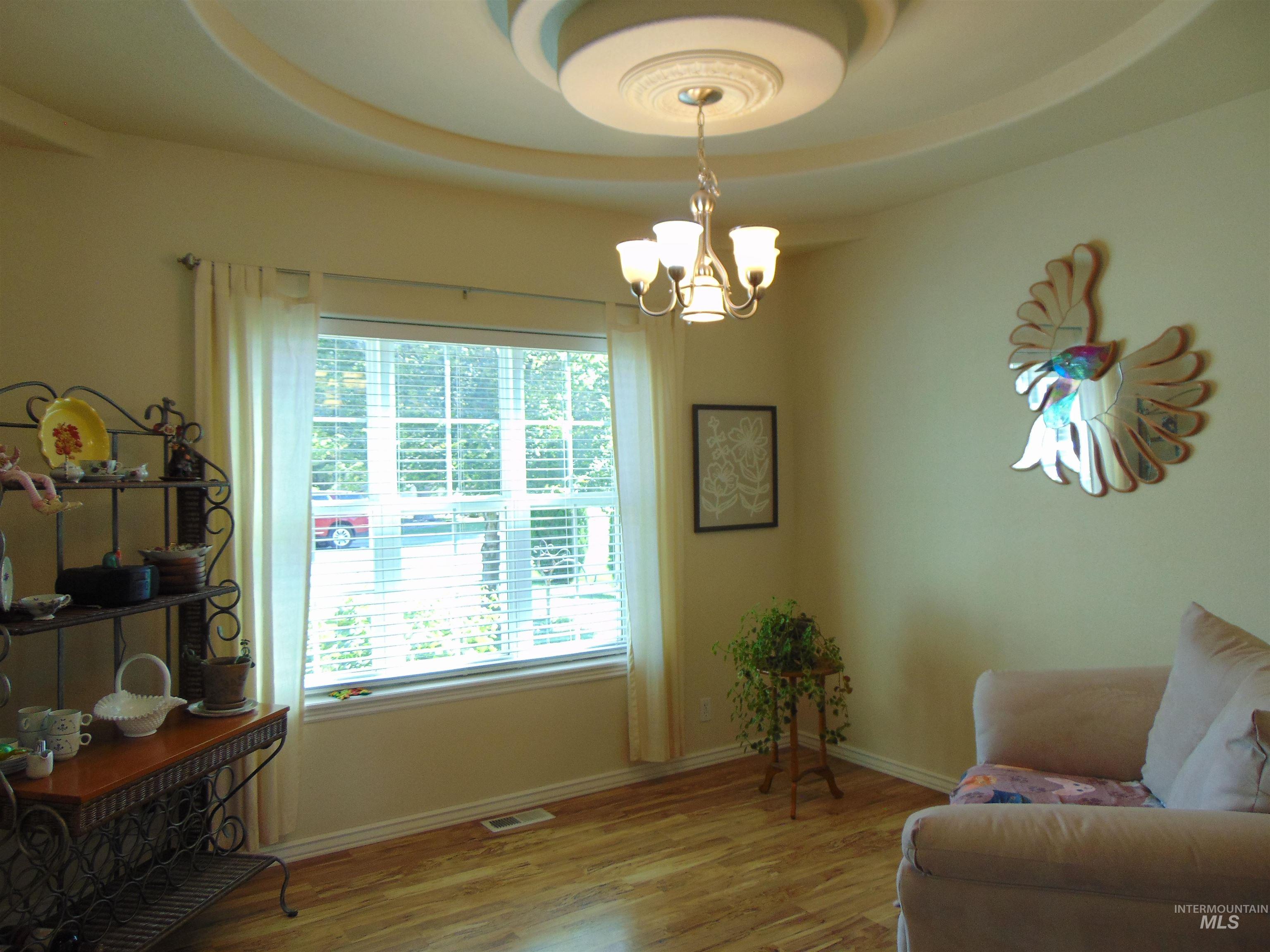 Sitting room featuring wood finished floors, a chandelier, and a tray ceiling
