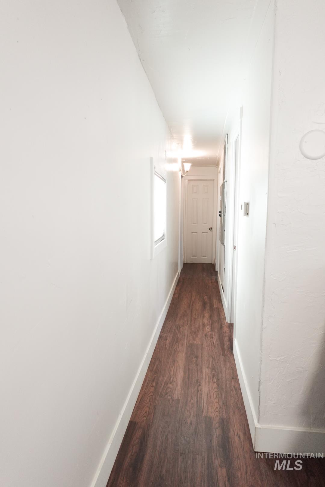 Hallway featuring dark wood finished floors and baseboards
