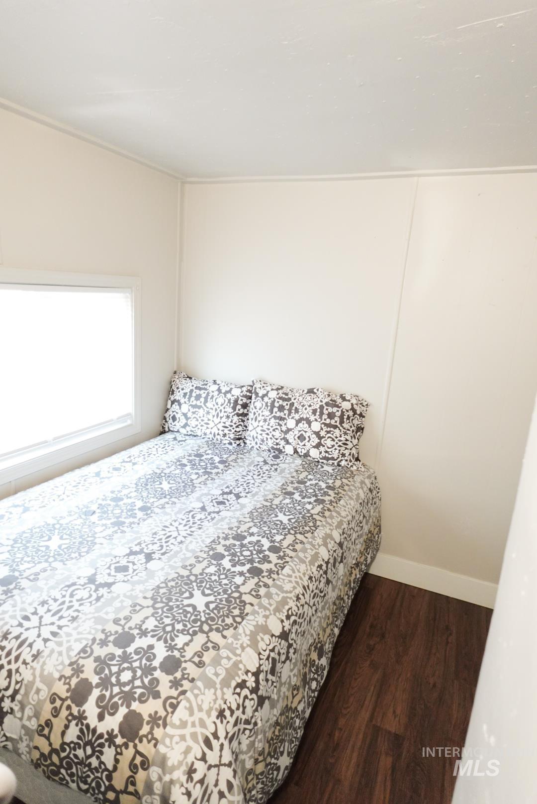 Bedroom featuring dark wood finished floors and baseboards