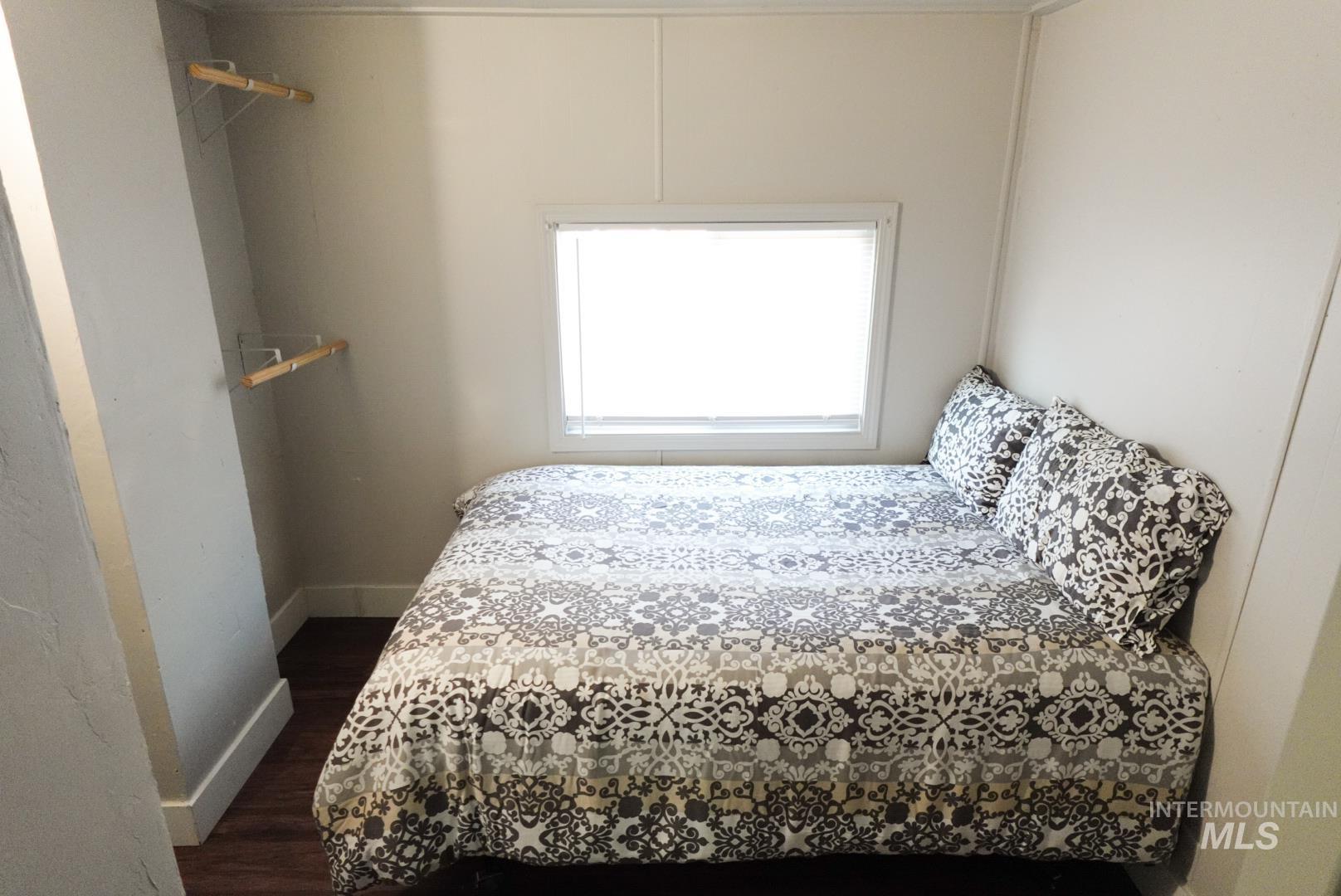 Bedroom featuring dark wood-style floors and baseboards
