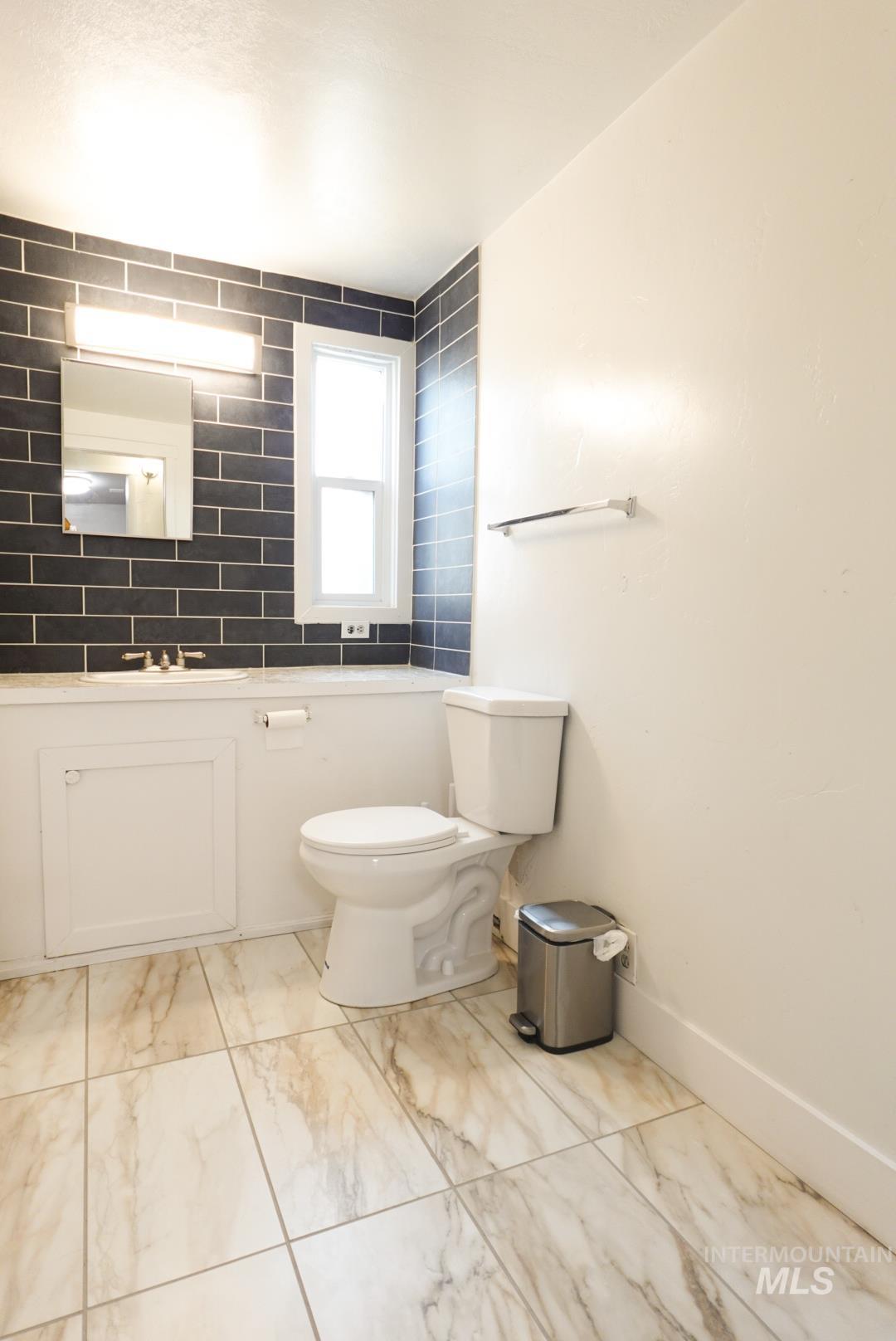 Half bathroom with light marble finish floors and vanity