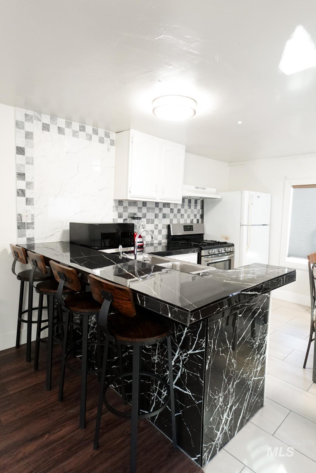 Kitchen with a breakfast bar, backsplash, a peninsula, and gas stove