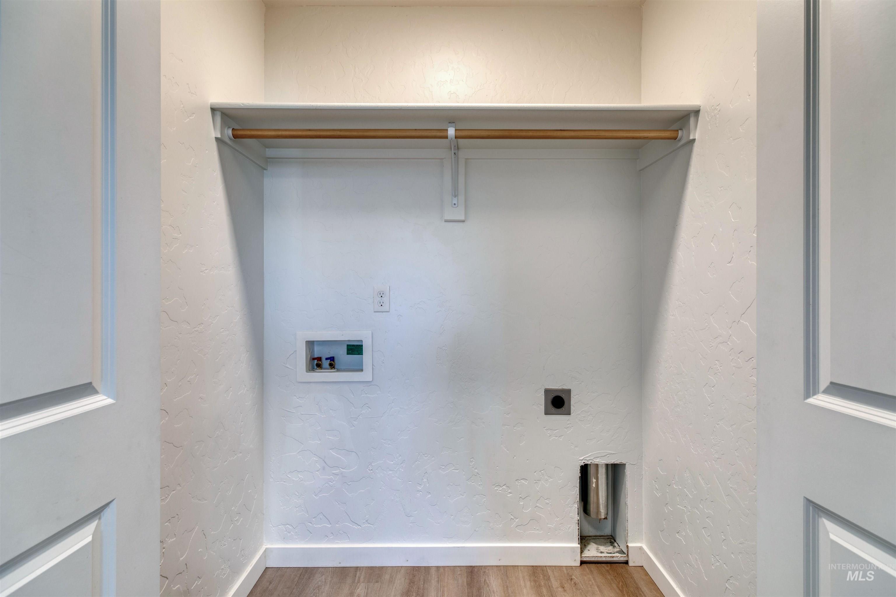 Laundry room featuring a textured wall, wood finished floors, hookup for a washing machine, and electric dryer hookup
