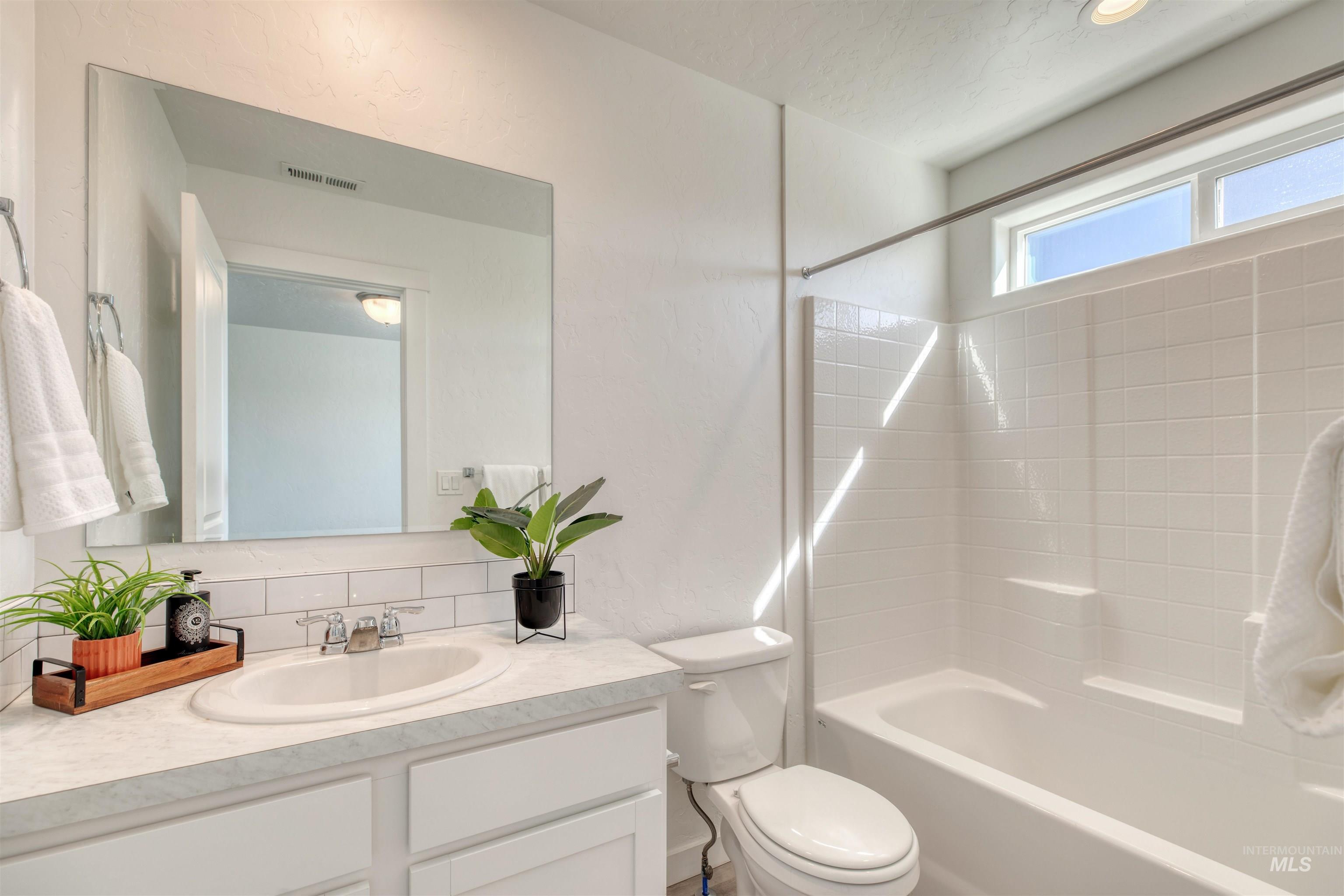 Bathroom featuring  shower combination, vanity, and backsplash