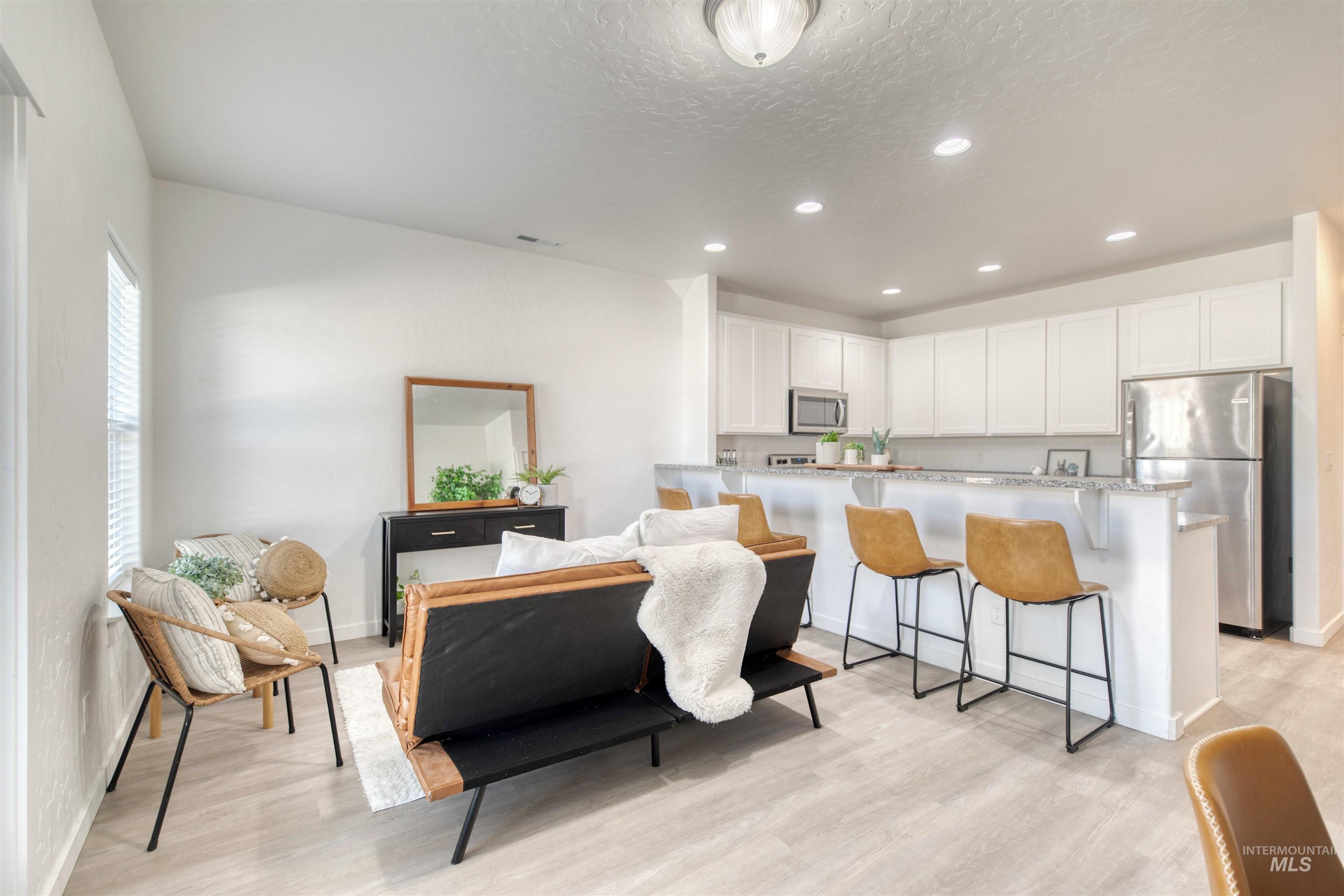Living room with recessed lighting, light wood-type flooring, and a textured ceiling