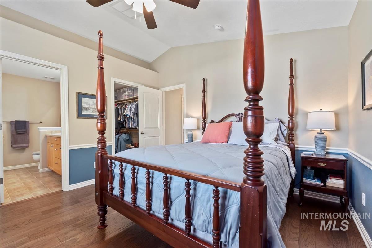 Primary Bedroom with a spacious walk-in closet, lofted ceiling, a ceiling fan, and en suite Bath
