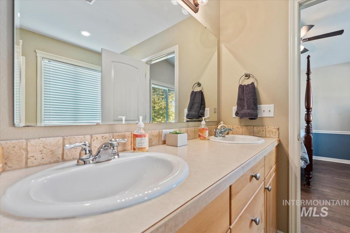 Primary Bedroom's en suite Bathroom, featuring double vanity, ceiling fan, and recessed lighting