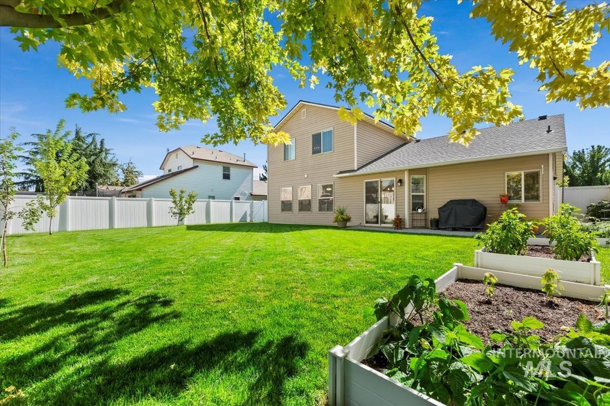 Rear view of house featuring a vegetable garden, a fenced backyard, and a patio