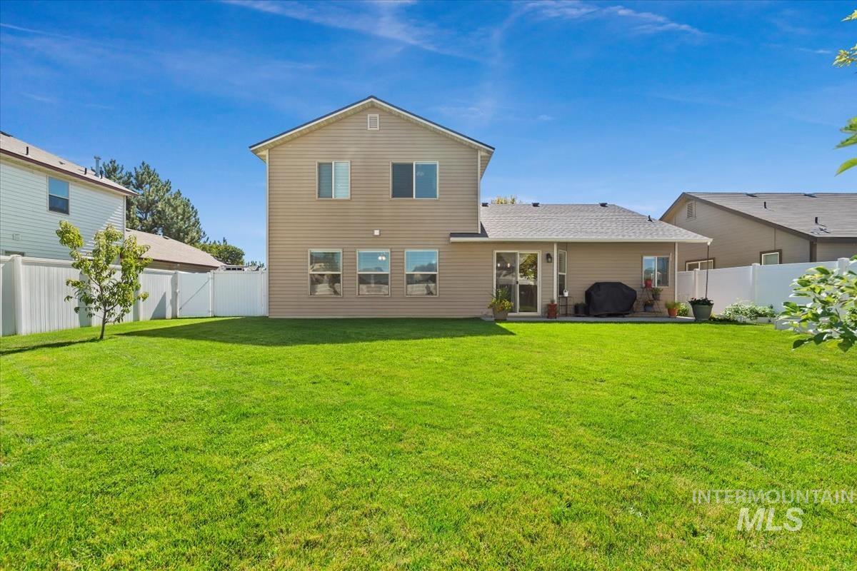 Rear view of house with a fenced backyard and a patio