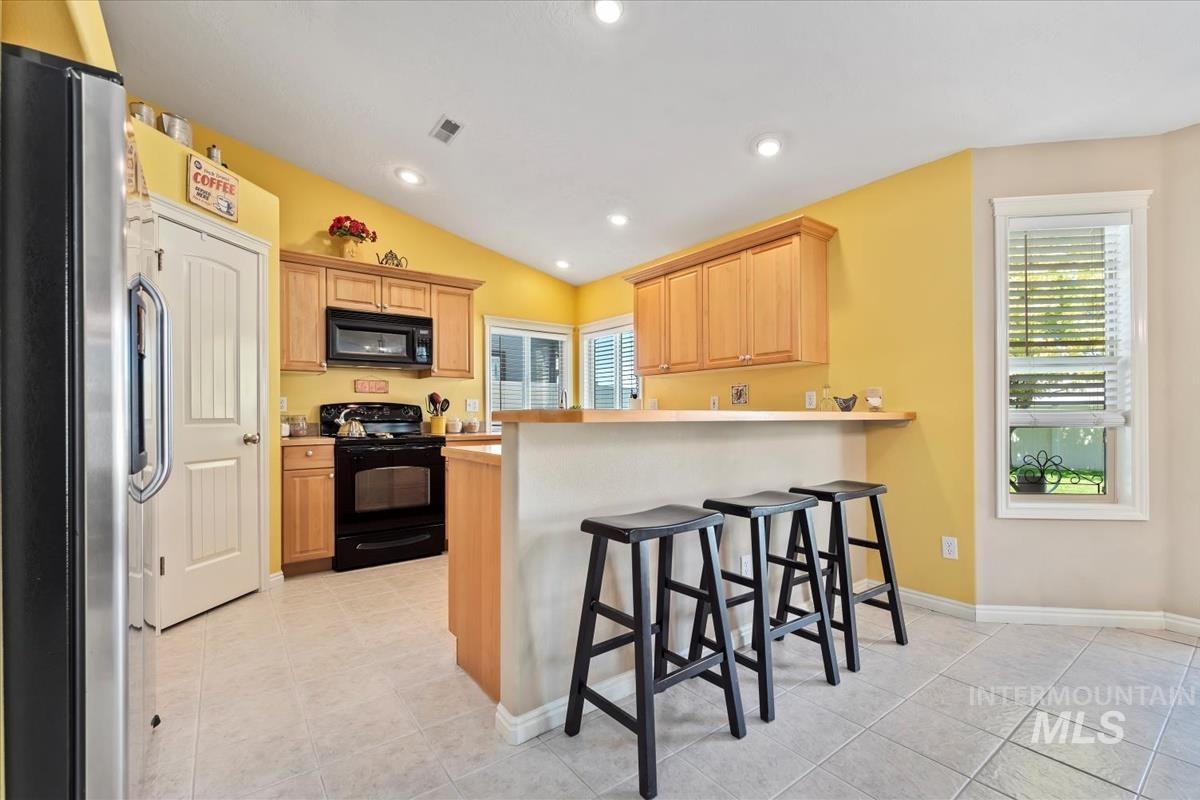 Kitchen with a breakfast bar, plenty of natural light, light brown cabinets, and recessed lighting