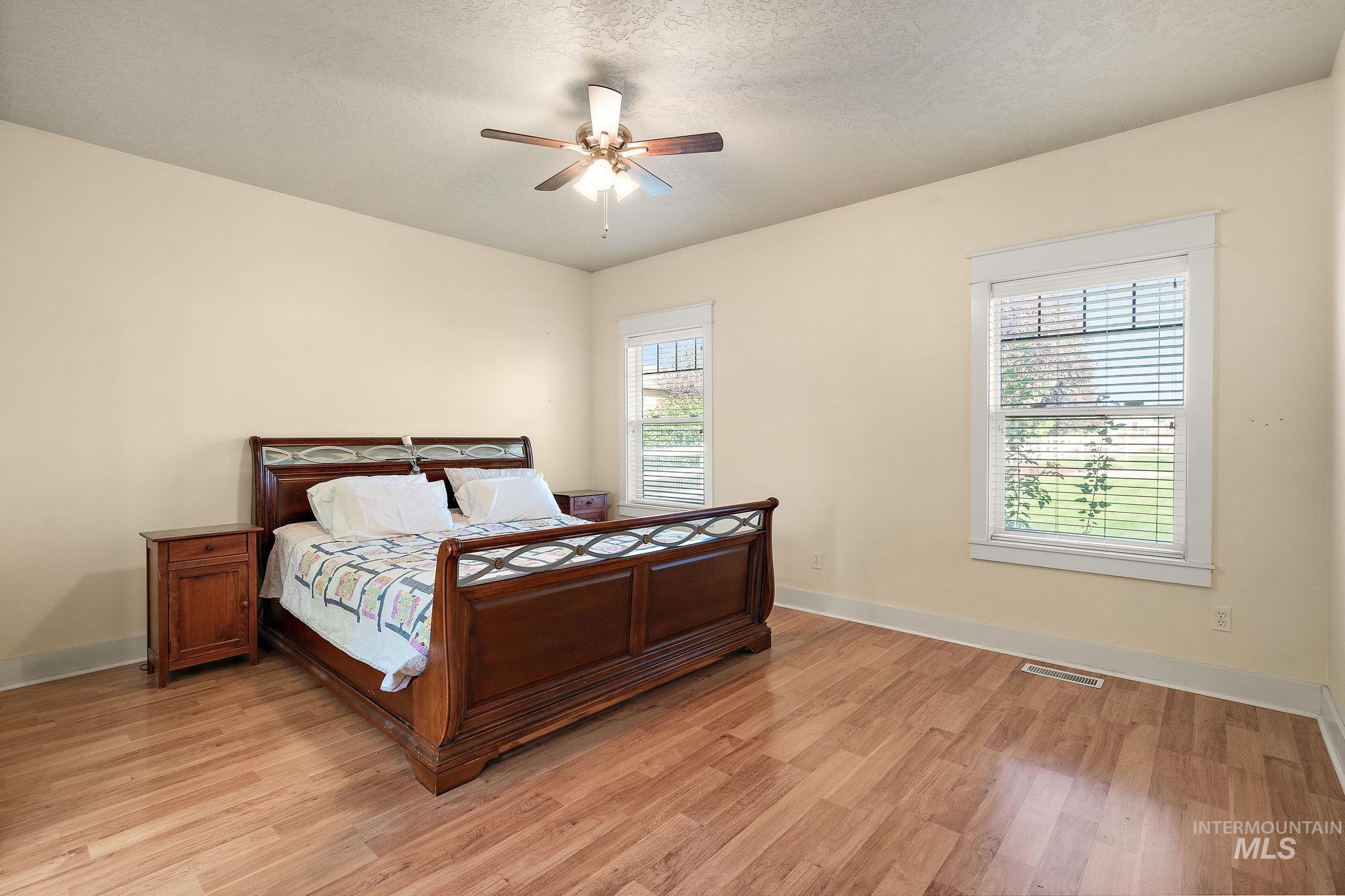 Bedroom with a textured ceiling, light wood-style flooring, and ceiling fan