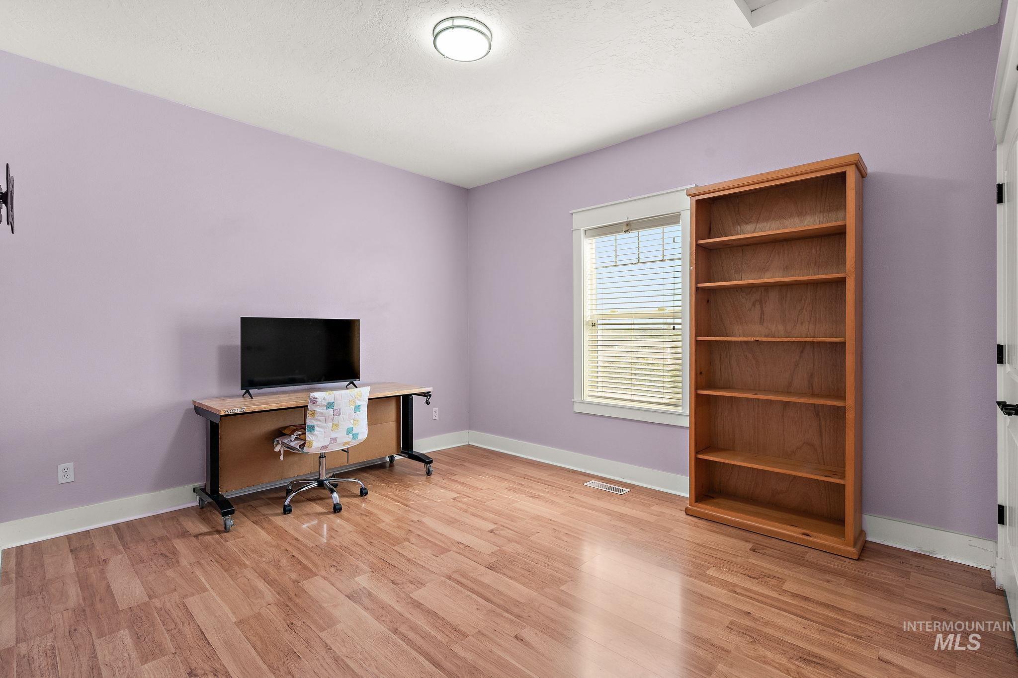 Office featuring light wood-type flooring and a textured ceiling