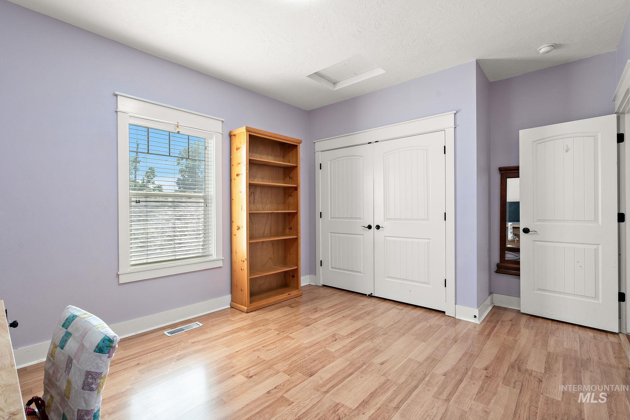 Bedroom featuring attic access, a closet, and light wood-style flooring