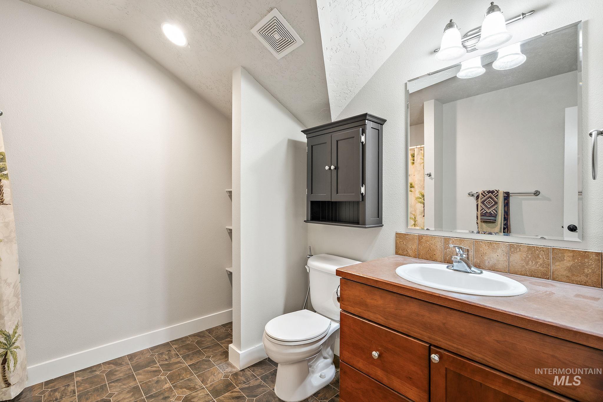 Bathroom featuring a textured ceiling, vanity, lofted ceiling, recessed lighting, and curtained shower