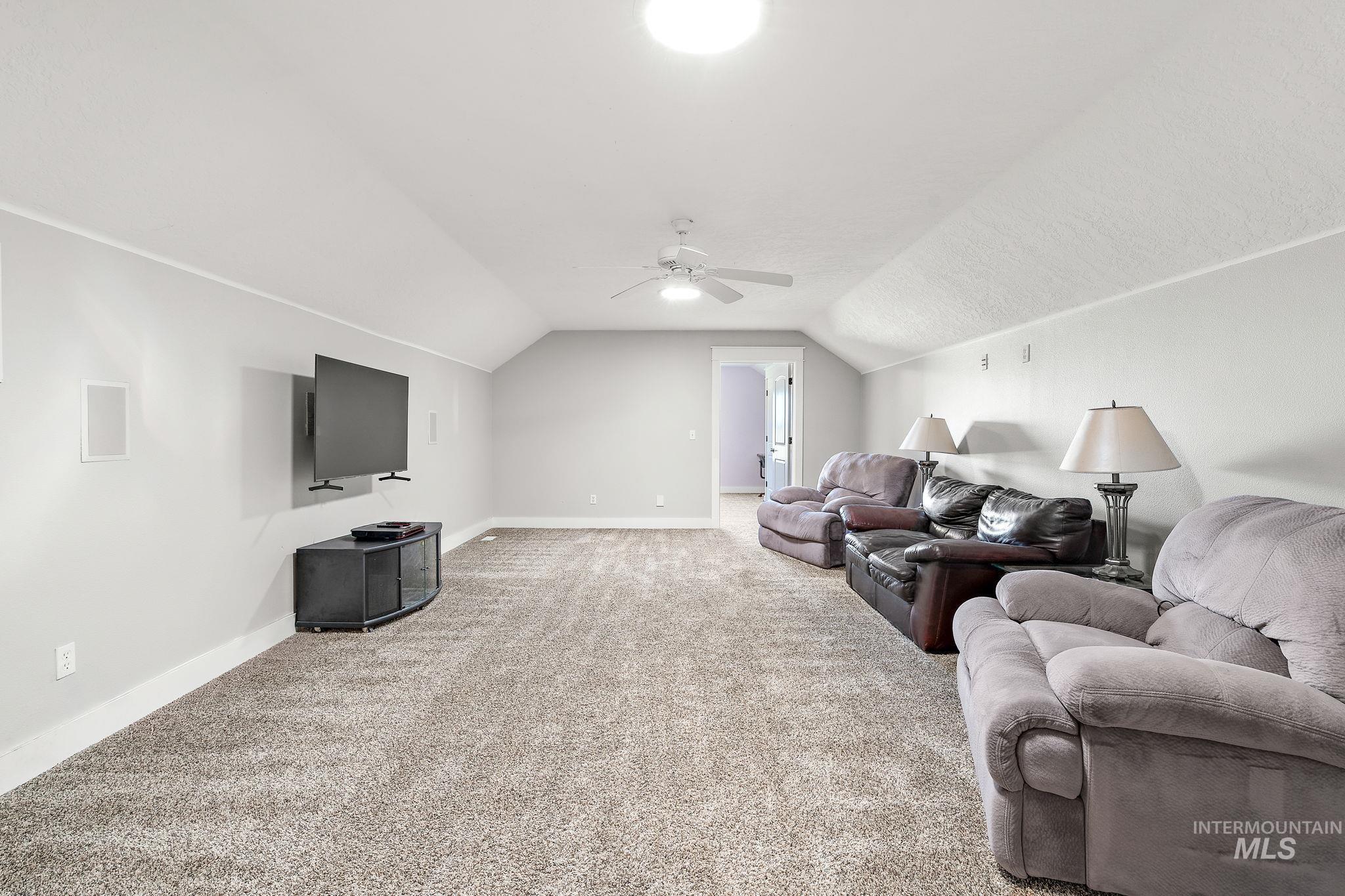 Living area with carpet, lofted ceiling, and a ceiling fan