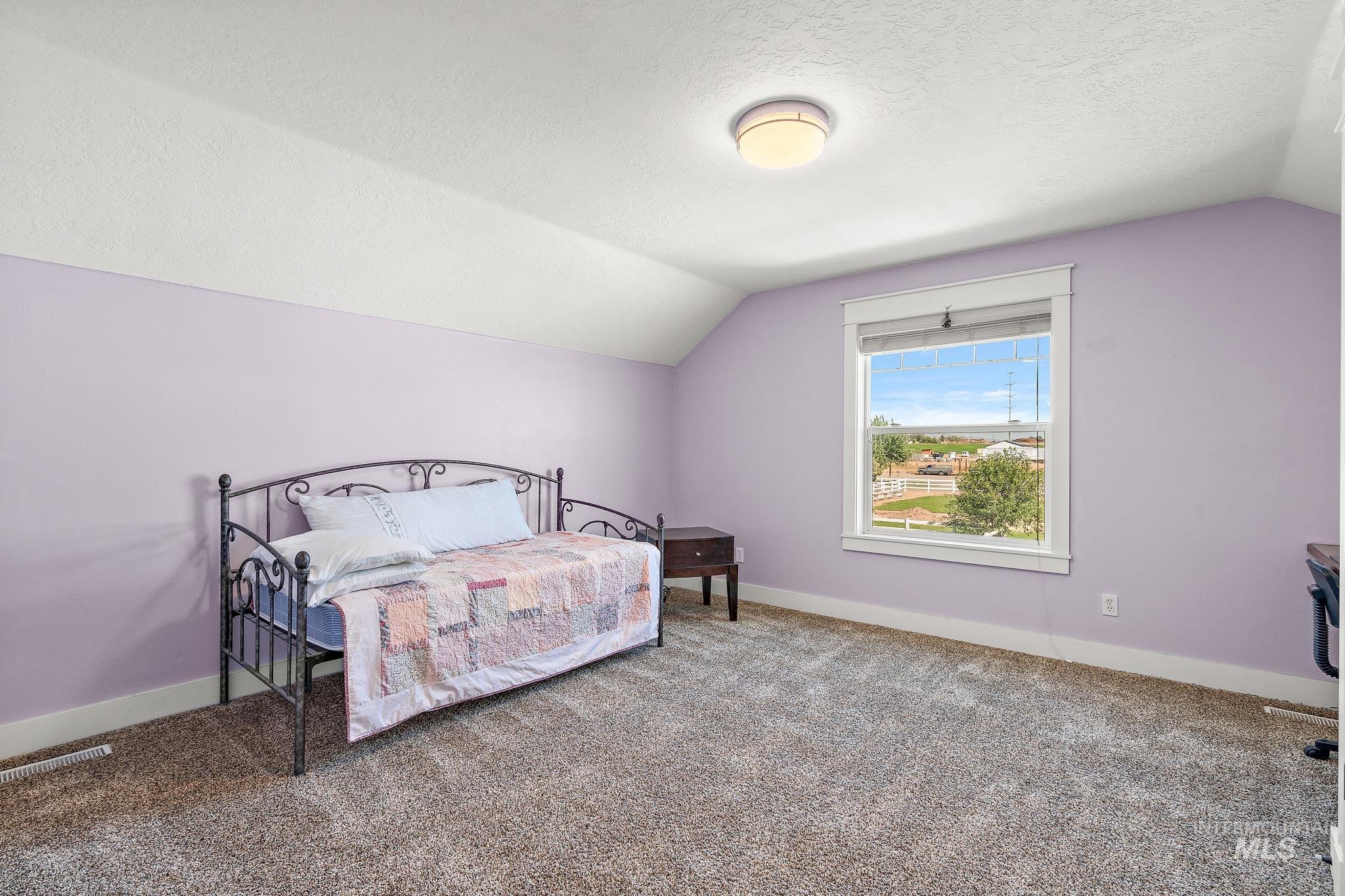 Bedroom featuring lofted ceiling, carpet floors, and a textured ceiling