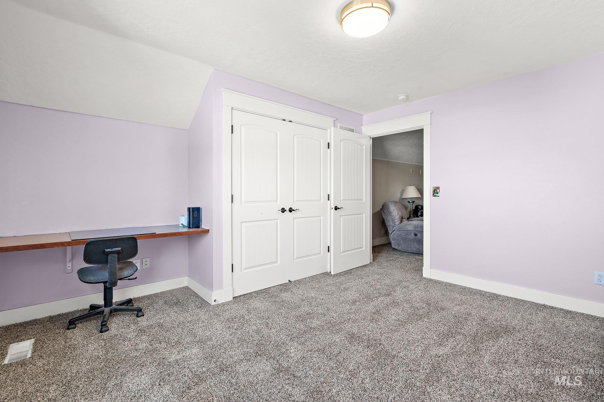 Unfurnished office with carpet floors, vaulted ceiling, and built in study area