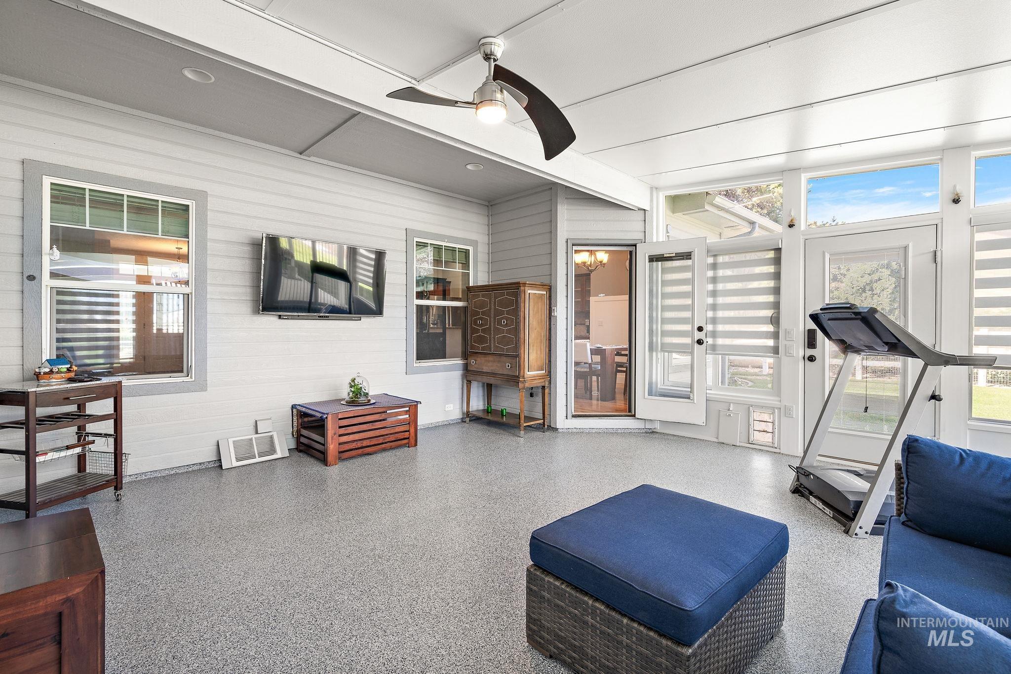 Exercise area featuring a ceiling fan, plenty of natural light, and wood walls