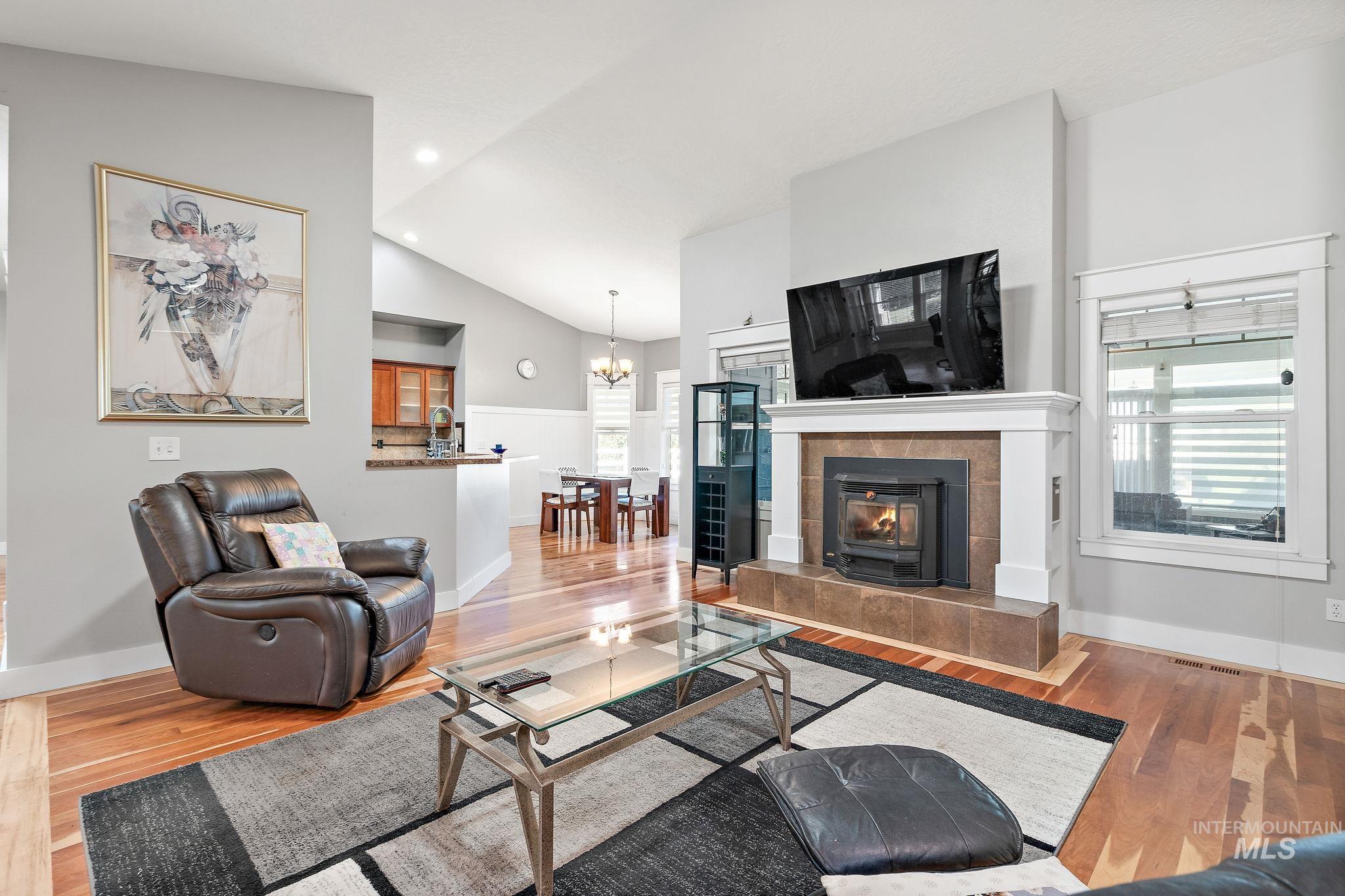 Living room featuring wood finished floors, vaulted ceiling, a chandelier, healthy amount of natural light, and recessed lighting