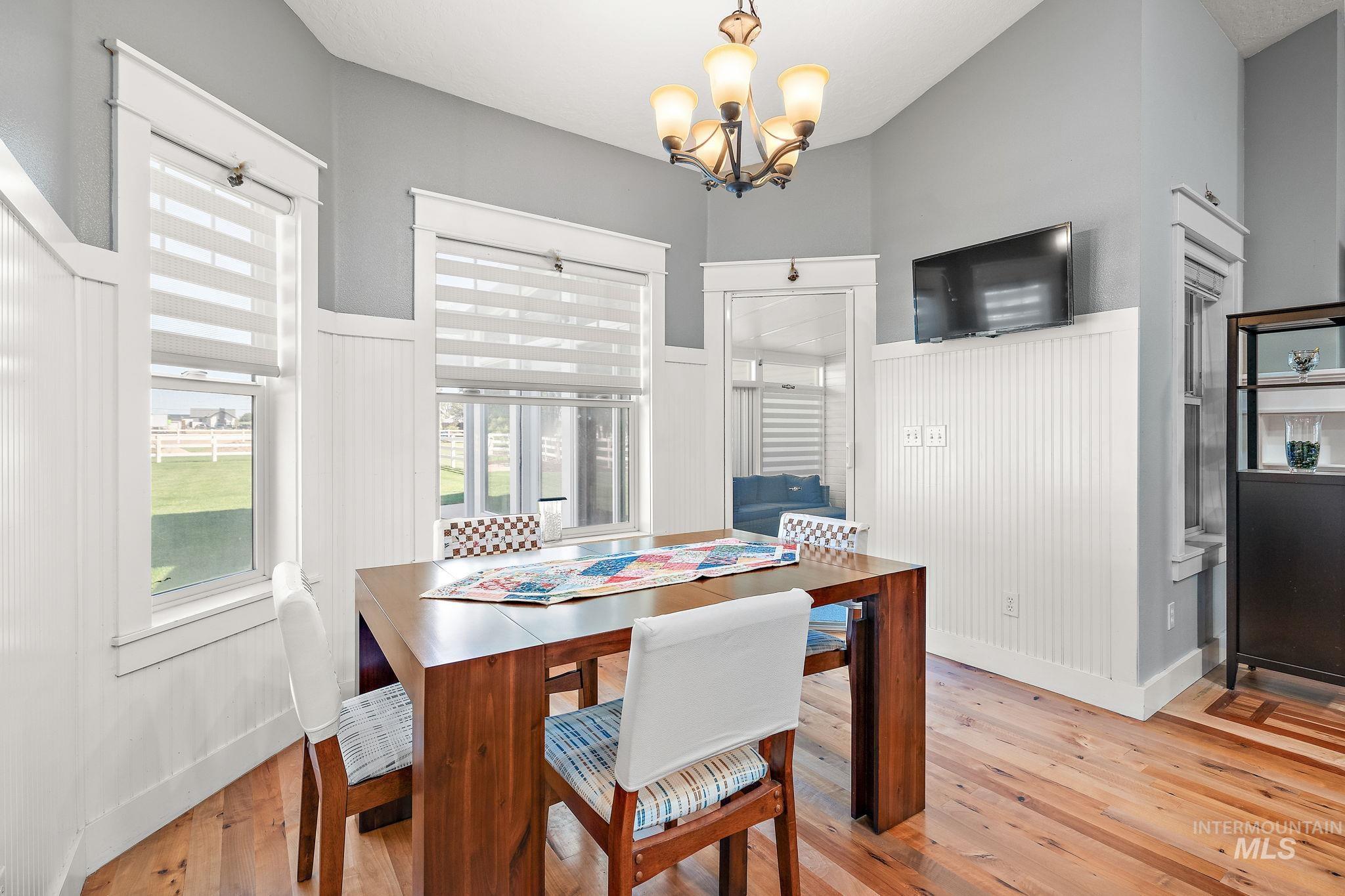 Dining area featuring light wood-style flooring, a chandelier, and a wainscoted wall