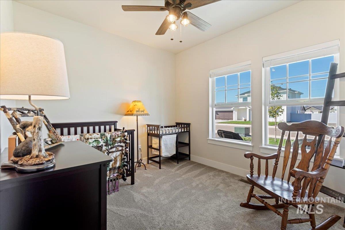 Living area with light colored carpet and a ceiling fan