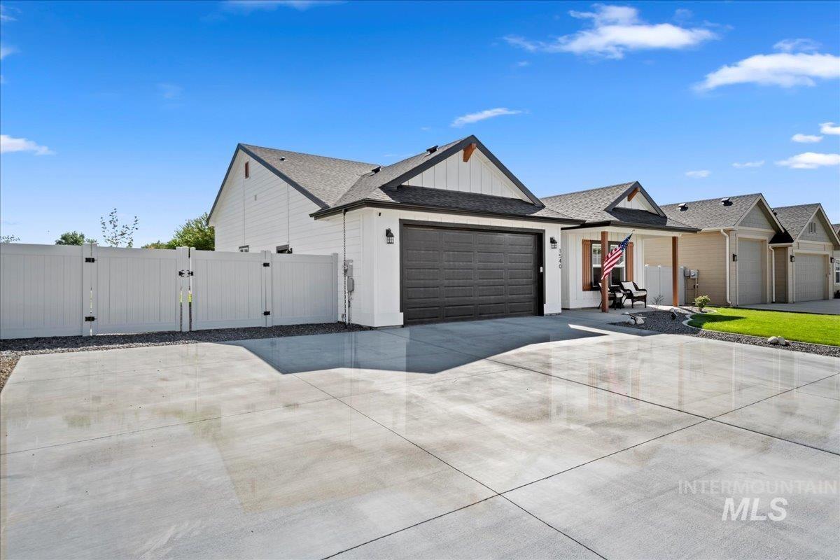 View of front facade featuring a gate, a shingled roof, driveway, an attached garage, and board and batten siding