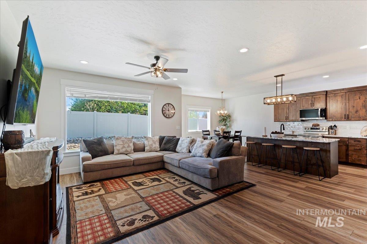 Living room with dark wood-style flooring, ceiling fan, recessed lighting, a chandelier, and a textured ceiling