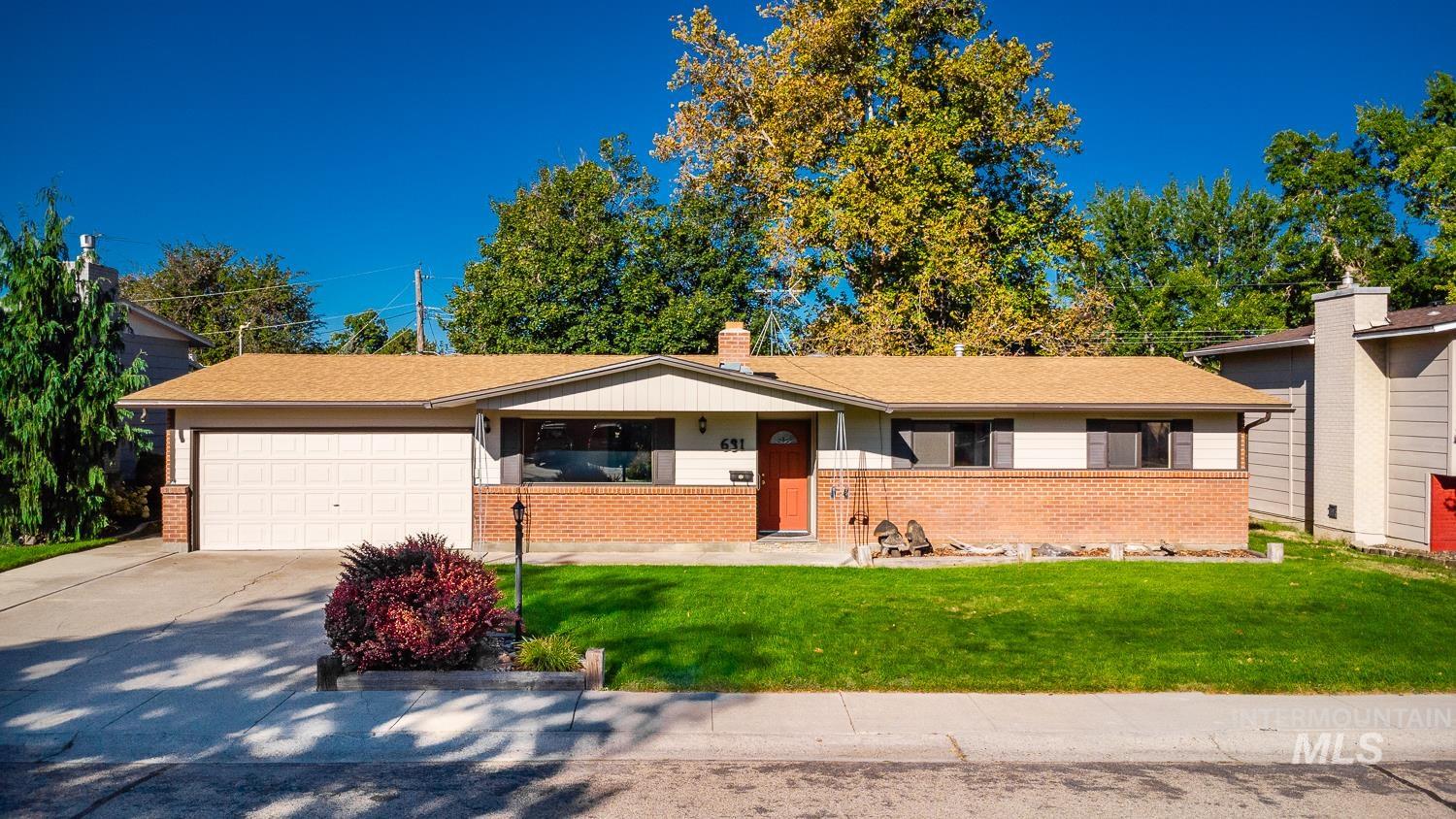 Ranch-style home with brick siding, a front yard, a garage, and driveway