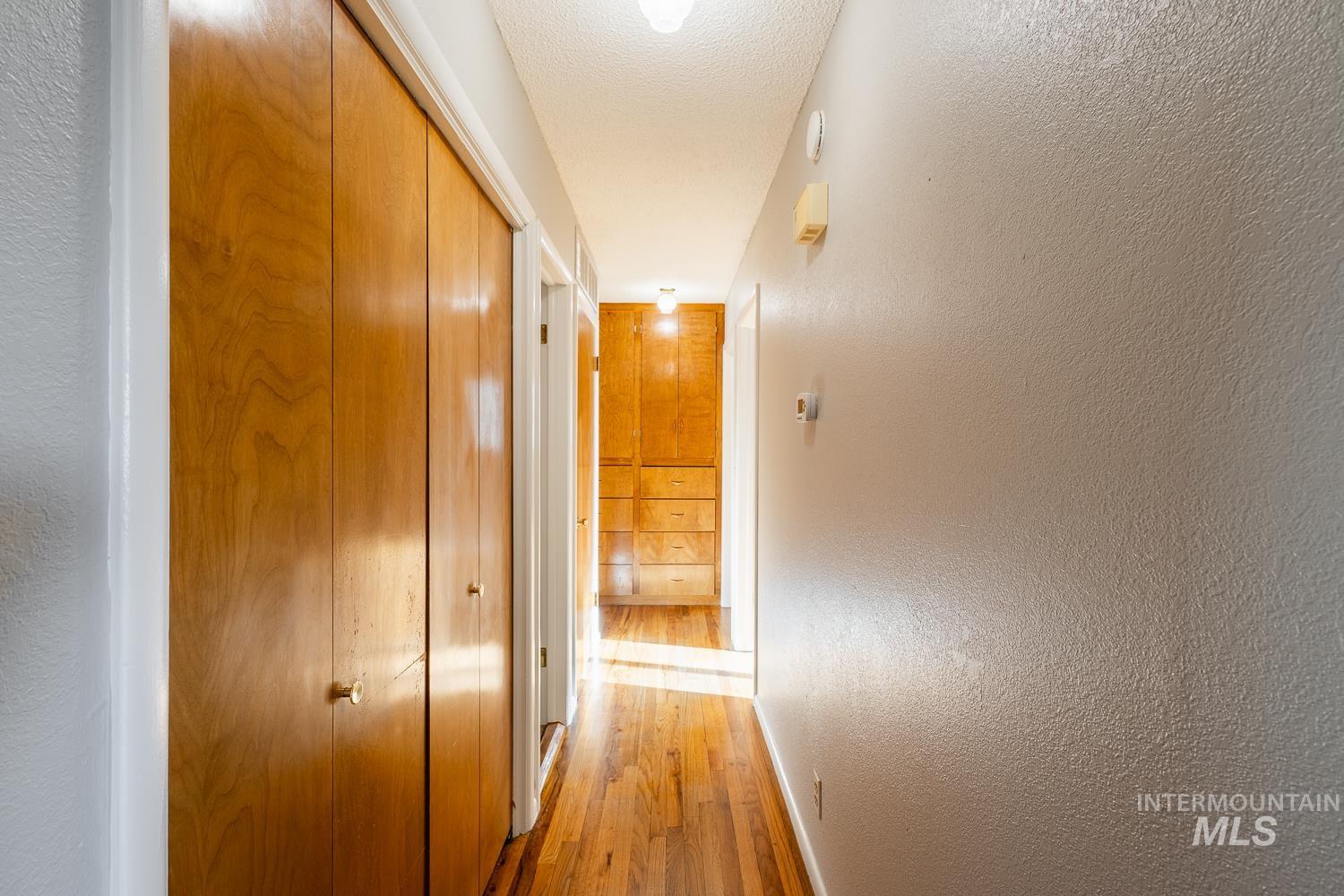 Hallway featuring a textured wall and wood finished floors