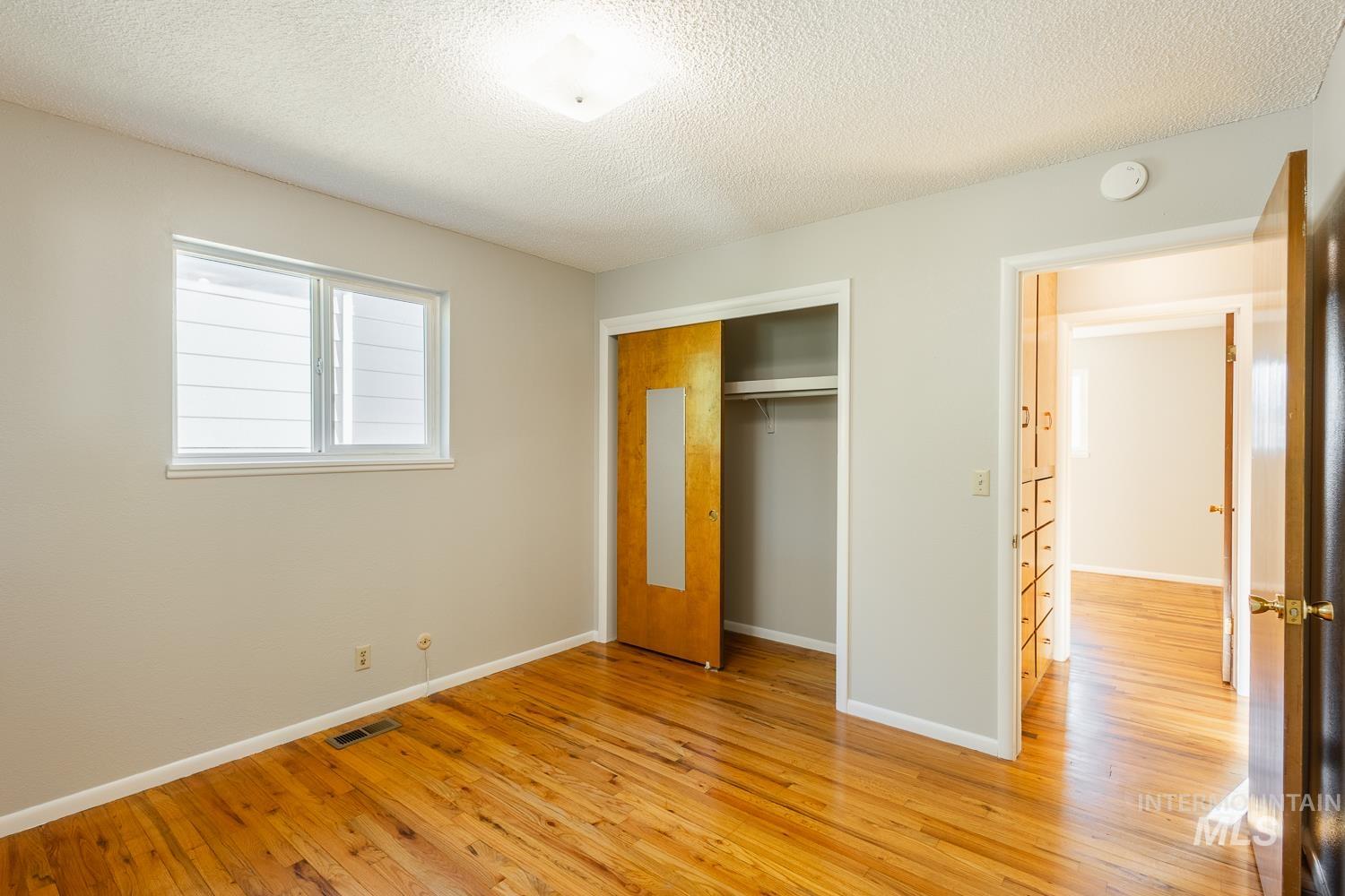 Unfurnished bedroom featuring a textured ceiling, light wood-style flooring, and a closet