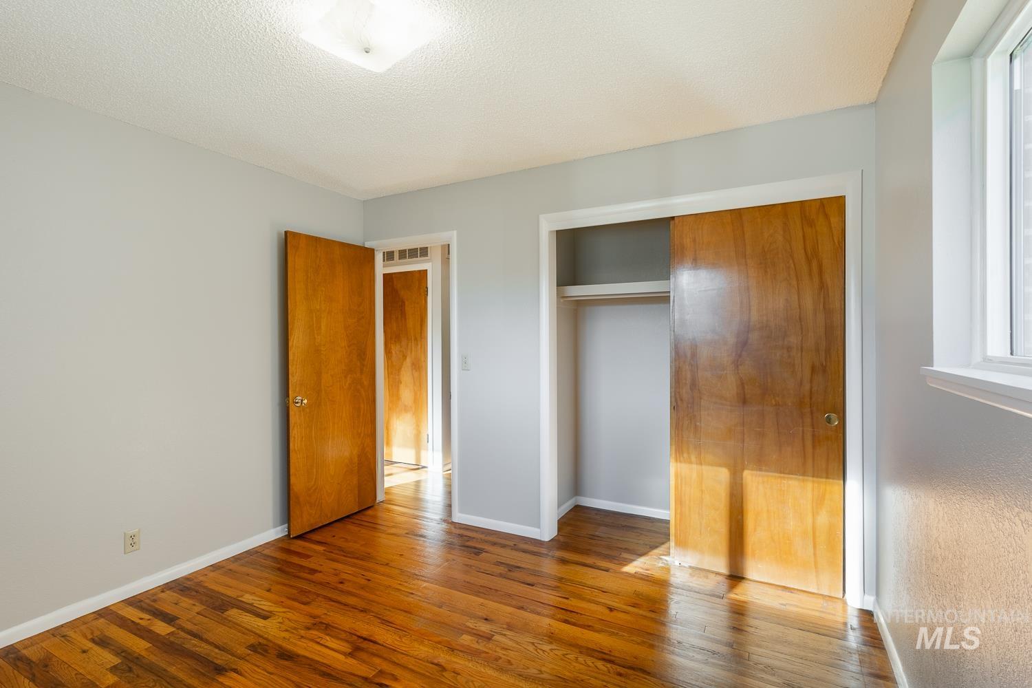 Unfurnished bedroom with hardwood / wood-style floors, a textured ceiling, and a closet