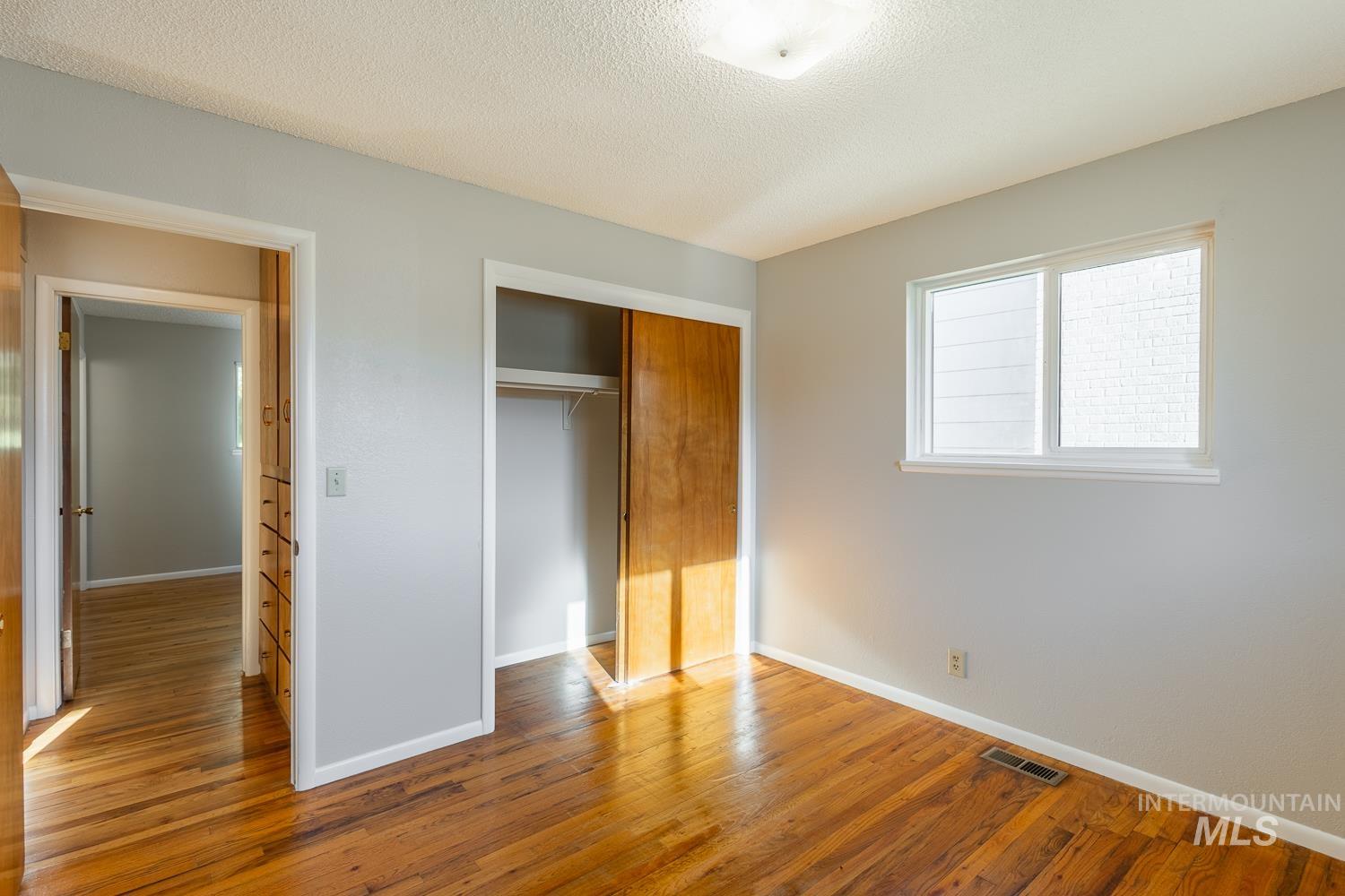 Unfurnished bedroom featuring wood finished floors, a textured ceiling, and a closet