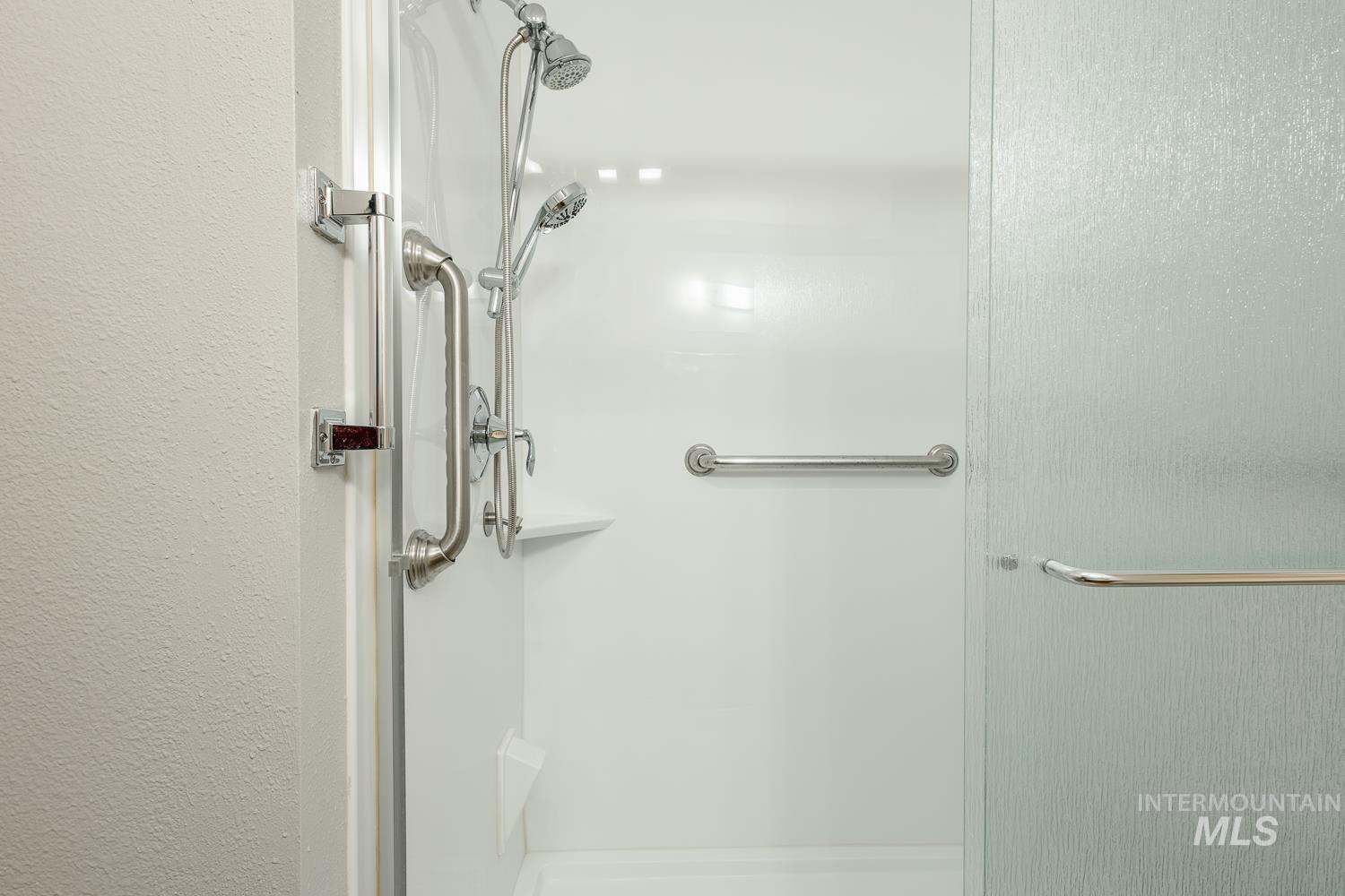 Full bathroom featuring a stall shower and a textured wall