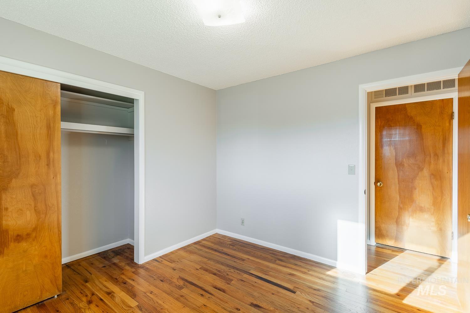 Unfurnished bedroom featuring a closet, wood-type flooring, and a textured ceiling