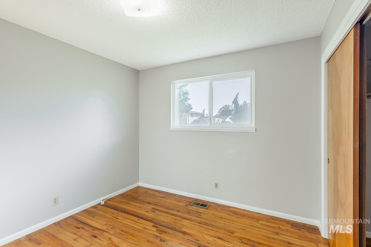 Unfurnished bedroom featuring a closet, wood finished floors, and a textured ceiling