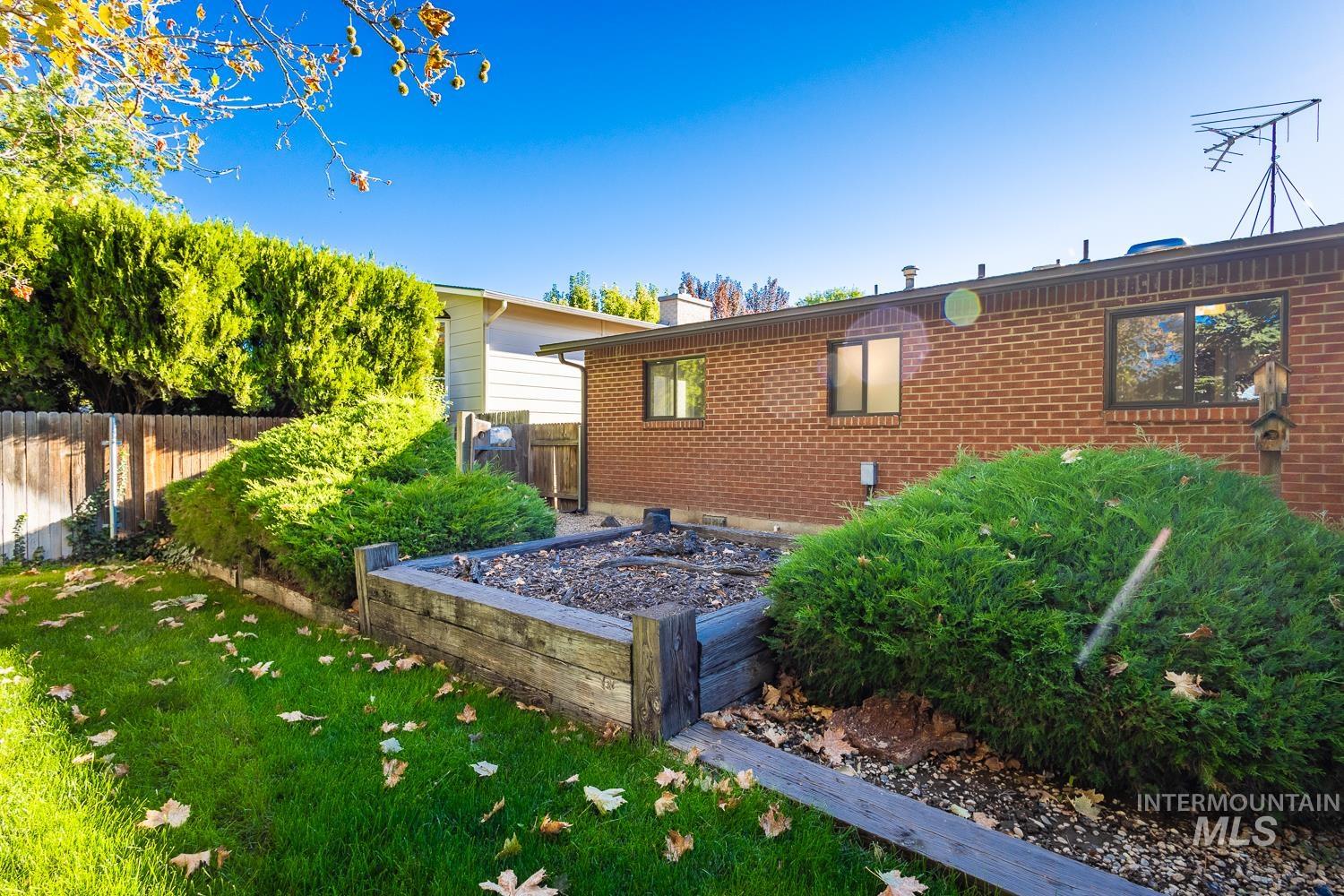 View of property exterior with a garden, brick siding, and a chimney