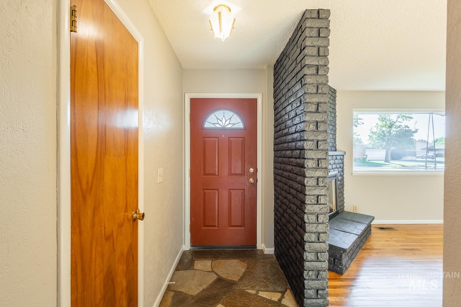 Doorway featuring a textured ceiling and wood finished floors