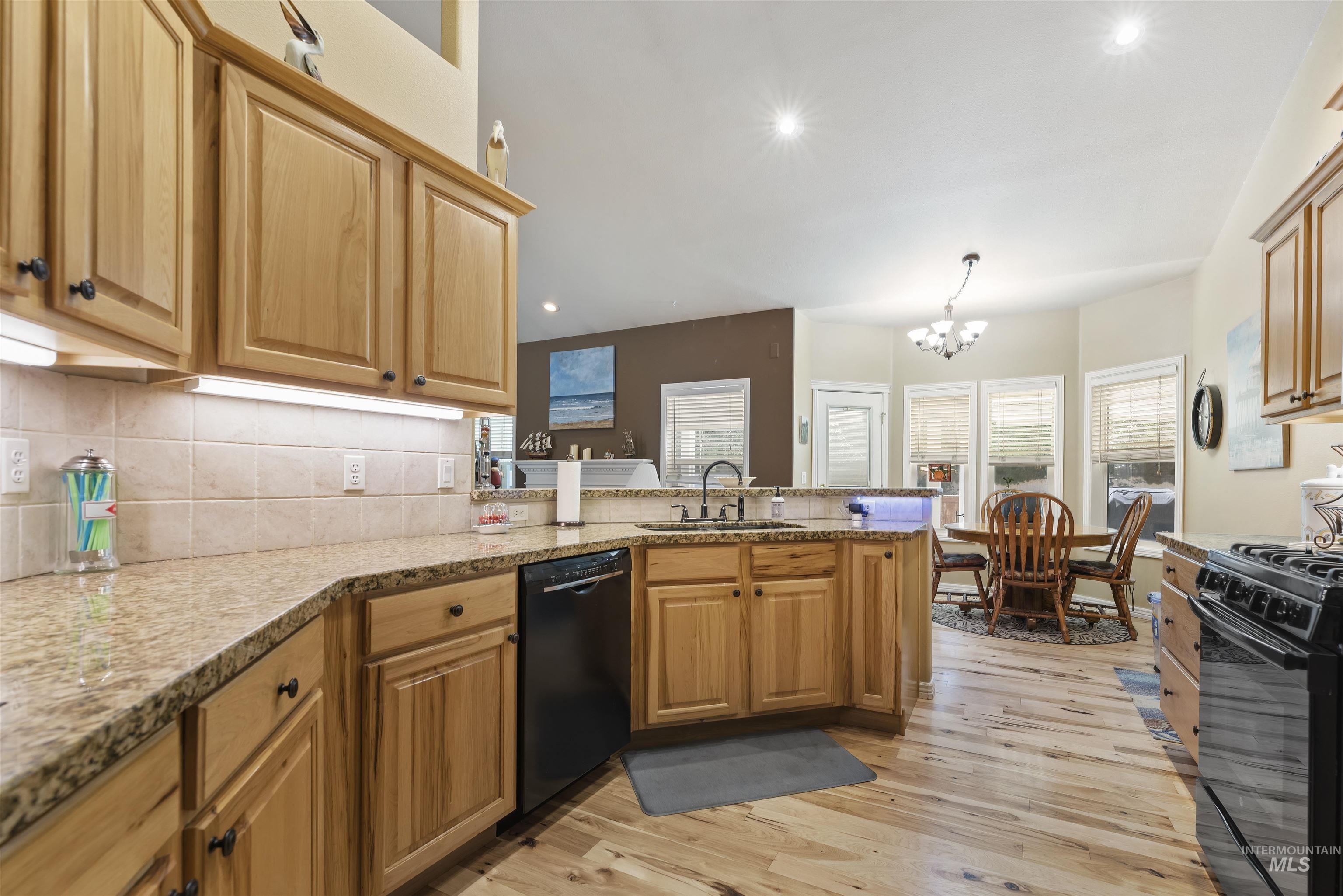 Kitchen featuring recessed lighting, light wood-type flooring, backsplash, black appliances, and a peninsula